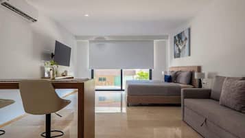 Una habitación de hotel moderna con cama, escritorio, silla, sofá, televisor y un gran ventanal.