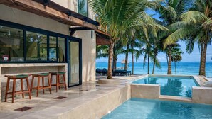 A poolside area with a bar and seating, overlooking the ocean. - Beachfront 7BR Villa with Private Pool and Sauna (Tulum)