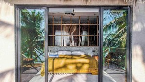 A room with a bed, a window, and a view of palm trees. - Beachfront 7BR Villa with Private Pool and Sauna (Tulum)