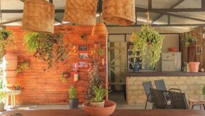 A rustic interior with wooden walls, hanging plants, and a bar area. - Chalés casa Borba  (Alto Paraíso de Goiás)