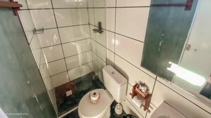 A small bathroom with a toilet, a shower area, and a mirror. - Chalés casa Borba  (Alto Paraíso de Goiás)