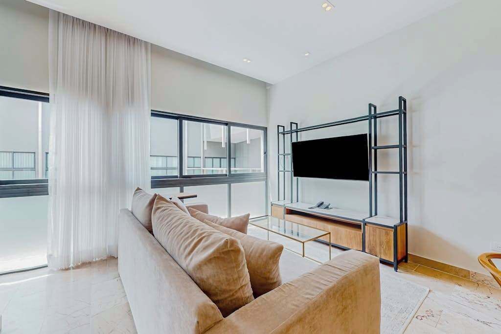 A modern living room with a sofa, a TV mounted on a wall, and a balcony with a railing.