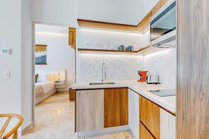 A modern kitchen with a marble countertop, wooden cabinets, and a built-in oven. - Playa 2BR | Rooftop Pool, Ocean View & Gym (Playa del Carmen)