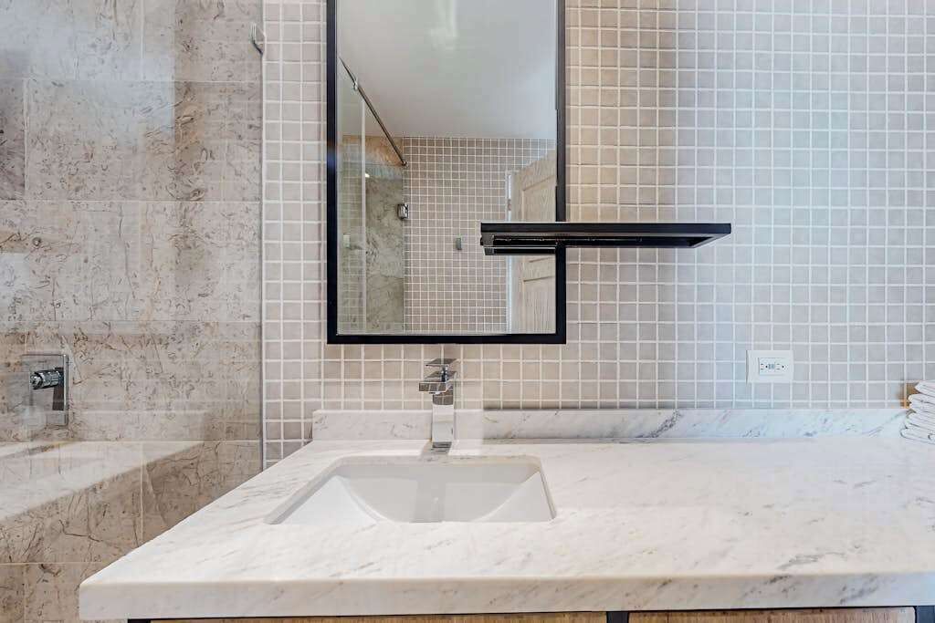 Une salle de bain avec un lavabo en marbre, un miroir et une douche.