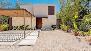 A modern house with a covered patio, a gravel driveway, and surrounding vegetation. - Xpu-Ha Beachfront Villa 1: Private Pool & Gym (Playa del Carmen)