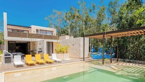 A modern two-story house with a pool, outdoor seating, and a covered patio area. - Xpu-Ha Beachfront Villa 1: Private Pool & Gym (Playa del Carmen)
