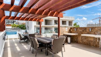 Un patio al aire libre con piscina, zona de comedor y pared de piedra.