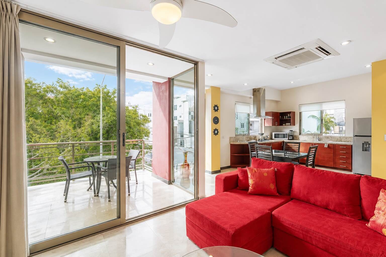 Una sala de estar moderna con un sofá rojo, un comedor y una cocina.