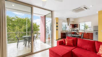 Una sala de estar moderna con un sofá rojo, un comedor y una cocina.