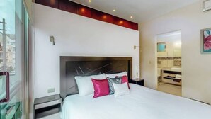 Een moderne hotelkamer met een groot bed, een hoofdeinde met verlichting, een nachtkastje en uitzicht op de stad door een raam.
