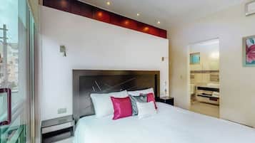 A modern hotel room with a large bed, a headboard with light fixtures, a bedside table, and a view of the city through a window.