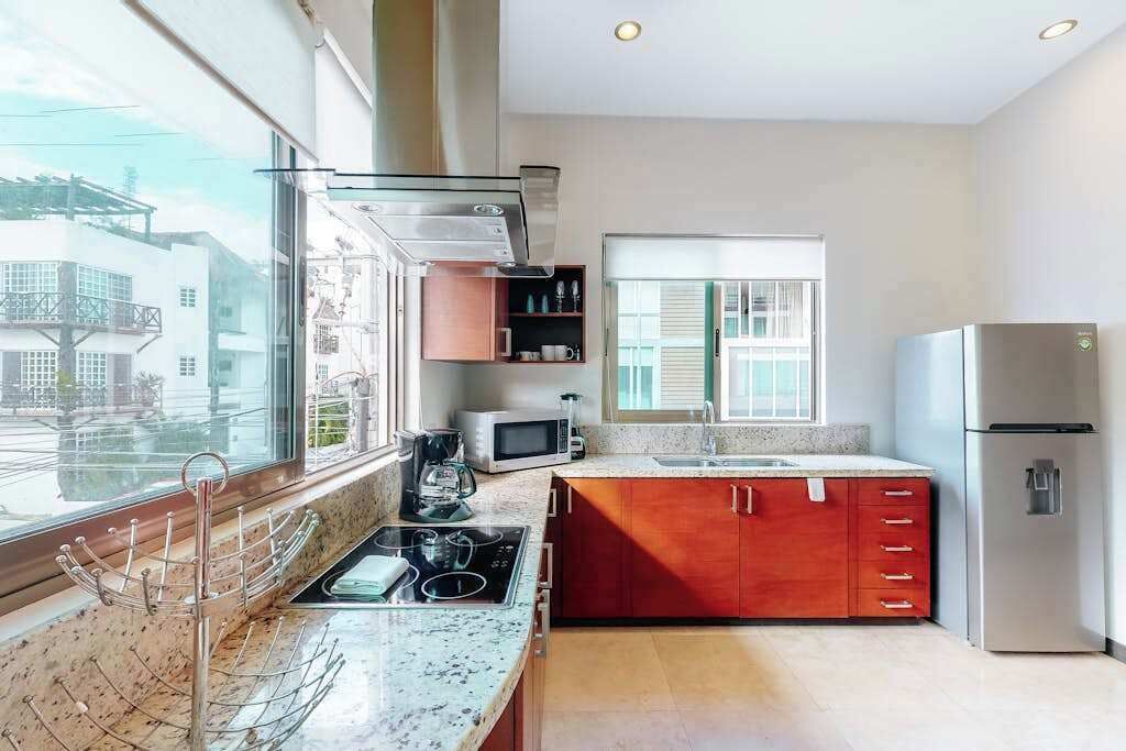 Una cocina moderna con un amplio ventanal, electrodomésticos de acero inoxidable y un armario rojo.
