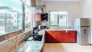 Een moderne keuken met een groot raam, roestvrijstalen apparatuur en een rode kast.