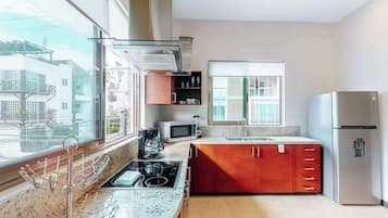 Una cocina moderna con un amplio ventanal, electrodomésticos de acero inoxidable y un armario rojo.