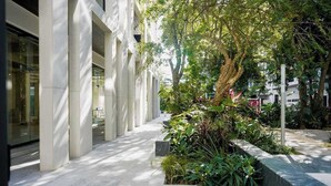 Un edificio moderno con una tettoia, vegetazione e cielo sereno.