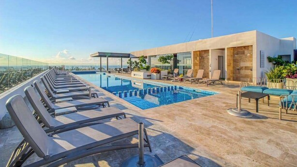 Una piscina sul tetto con lettini e un edificio moderno con ampie finestre.
