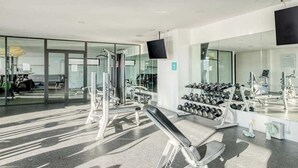 Una palestra moderna con attrezzature per esercizi, uno specchio e un televisore.