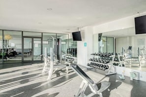 Ein modernes Fitnessstudio mit Trainingsgeräten, einem Spiegel und einem Fernseher.