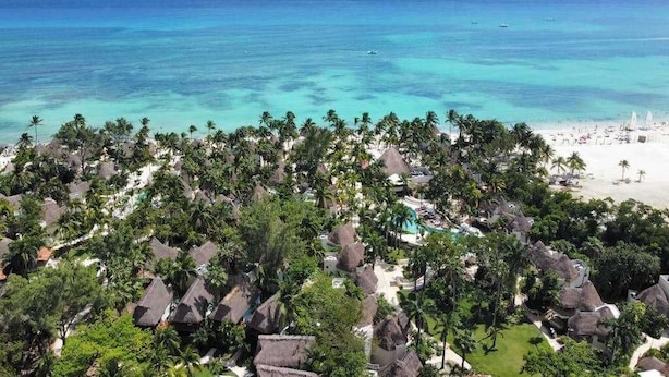 Ein Resort mit strohgedeckten Gebäuden, einem Strand und Blick auf den Ozean.