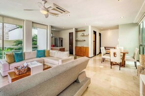 A modern living room with a sofa, coffee table, and dining area. - Stylish 1BR Condo: Beach, Rooftop Pool & 5th Ave (Playa del Carmen)