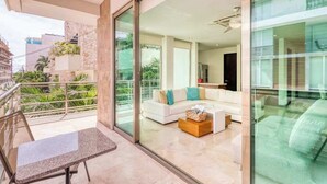 Uma sala de estar moderna com um sofá branco, uma mesa de centro e uma varanda com porta de vidro.