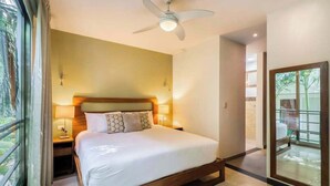 Quarto com cama, abajures, ventoinha no teto e vista por uma porta de vidro.