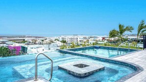 A rooftop infinity pool with a clear view of the cityscape and ocean. - Bright Condo: Rooftop Ocean Pool, Walk to Beach (Playa del Carmen)