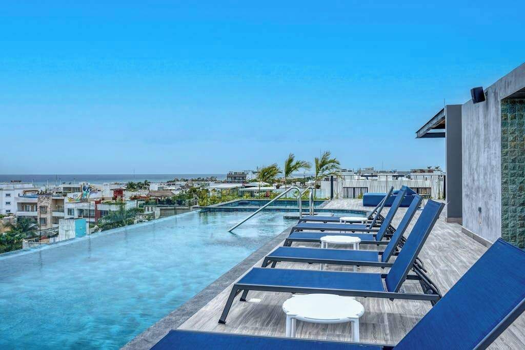 A rooftop pool with lounge chairs and a view of the city.