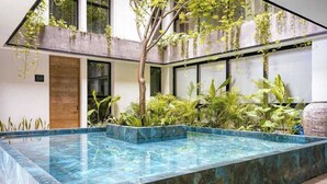 A modern indoor pool with a clear blue water feature, surrounded by lush greenery and a minimalist architectural design. - Bright Condo: Rooftop Ocean Pool, Walk to Beach (Playa del Carmen)