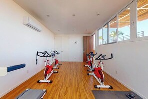 Ein Fitnessraum mit Ergometer, Laufband und Holzboden.