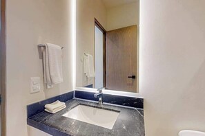 A bathroom with a sink, mirror, and towel rack. - Modern 1BR Condo | Rooftop Pool & Gym, Near Beach (Playa del Carmen)