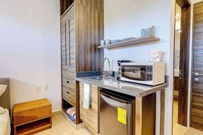 A compact kitchen with a microwave, sink, and wooden cabinets. - Stylish Studio near Akumal - Rooftop Pool & WiFi (Akumal)