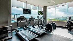 Une salle de sport équipée de tapis de course, d’un vélo d’appartement et d’un banc de musculation.