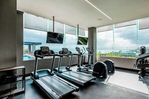 A gym with treadmills, a stationary bike, and a weight bench. - Ocean-View Condo - Rooftop Infinity Pool & WiFi (Playa del Carmen)