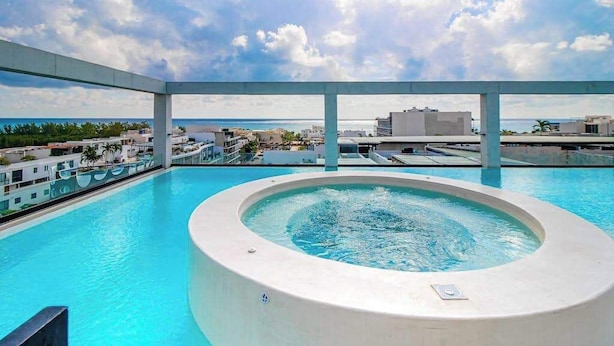 A rooftop pool with a hot tub, clear skies, and a view of the cityscape. - Playa Studio | Rooftop Pool & Balcony (Playa del Carmen)