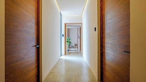 A hallway with wooden doors, a plant, and a small table. - Playa Studio | Rooftop Pool & Balcony (Playa del Carmen)