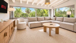 Uma sala de estar moderna com um sofá modular, uma mesa de centro redonda e uma TV fixada na parede.