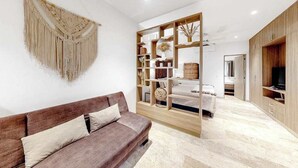Ein modernes Wohnzimmer mit einem braunen Sofa, einem dekorativen Wandbehang aus Makramee, einem Holzregal und einem Fernseher auf der rechten Seite.