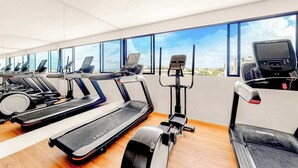 Ein Fitnessstudio mit Laufbändern, Crosstrainern und Rudergeräten.
