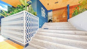 Eine Treppe führt zu einem Gebäudeeingang mit einer blauen Wand und einer Holzbalkendecke.