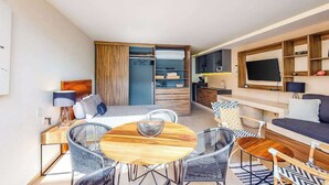 Een moderne hotelkamer met een zithoek, een bank, een televisie en een kledingkast.