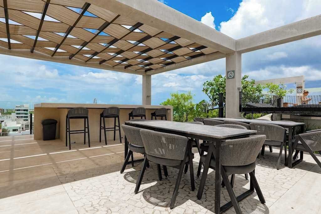 An outdoor patio with a wooden pergola, a bar area, and seating.