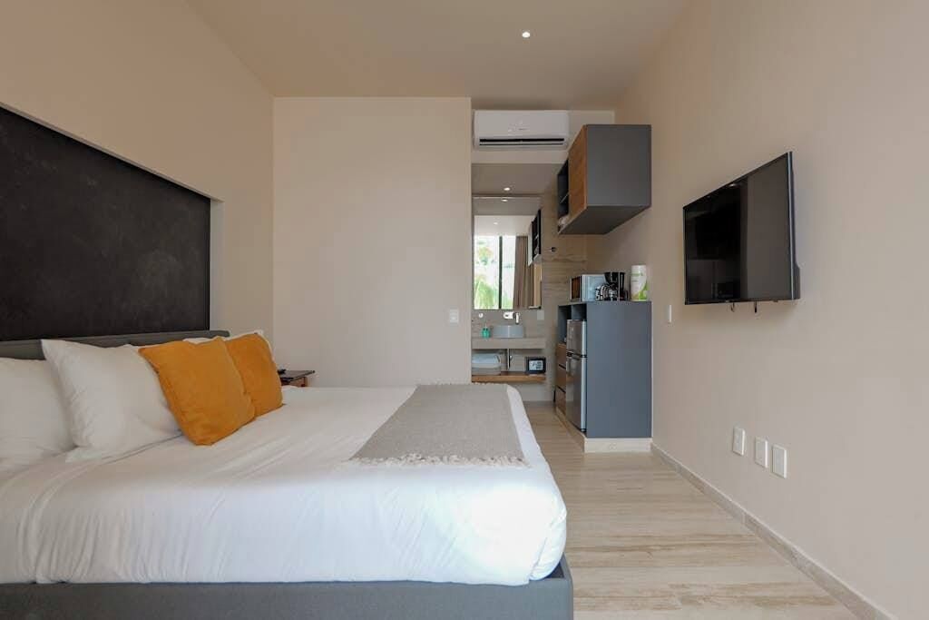 Un dormitorio con cama, televisión y kitchenette.