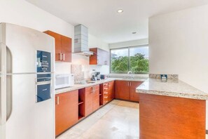 Een moderne keuken met een ingebouwde magnetron, een koelkast van roestvrij staal en houten keukenkastjes.