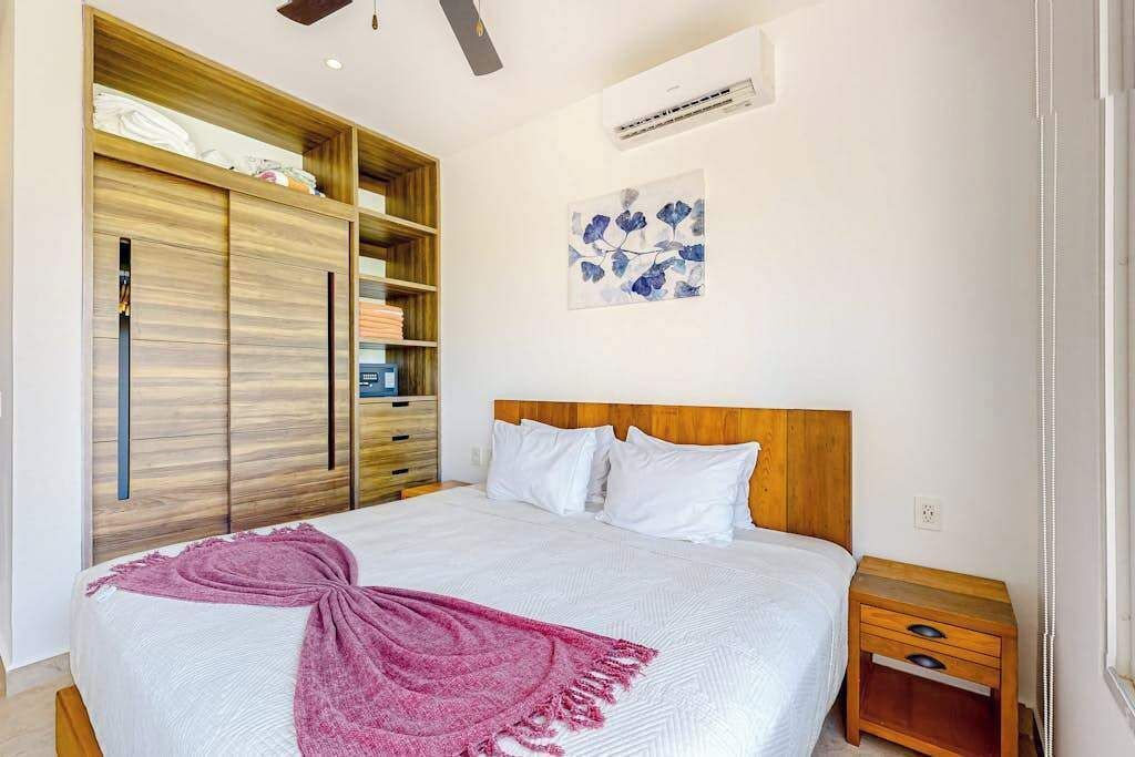 Une chambre à coucher avec un lit, une armoire en bois et un climatiseur fixé au mur.