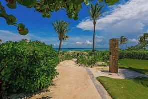 A pathway leading to a beach with palm trees and a clear sky. - Oceanfront Studio | Pool & Beach | Playa (Playa del Carmen)