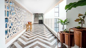 A corridor with a chevron-patterned floor, a decorative wall, and potted plants. - Oceanfront 2BR, Rooftop Pool, Gym, Walk to Beach (Playa del Carmen)