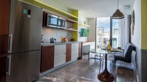 A modern kitchen with a built-in microwave, stainless steel refrigerator, and a dining area with a glass table and chairs. - Oceanfront 2BR, Rooftop Pool, Gym, Walk to Beach (Playa del Carmen)
