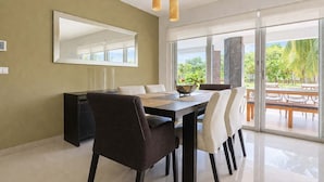 A dining area with a large table, chairs, a bowl, and a mirror on the wall. - Beachfront 3BR Condo, Resort Pool | Playa (Playa del Carmen)