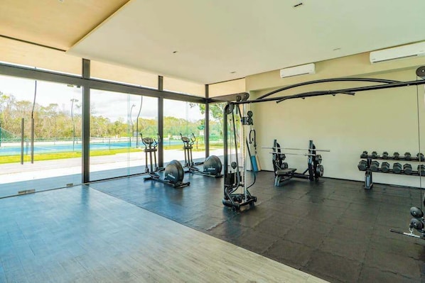 A modern gym with cardio equipment, weight machines, and dumbbells.